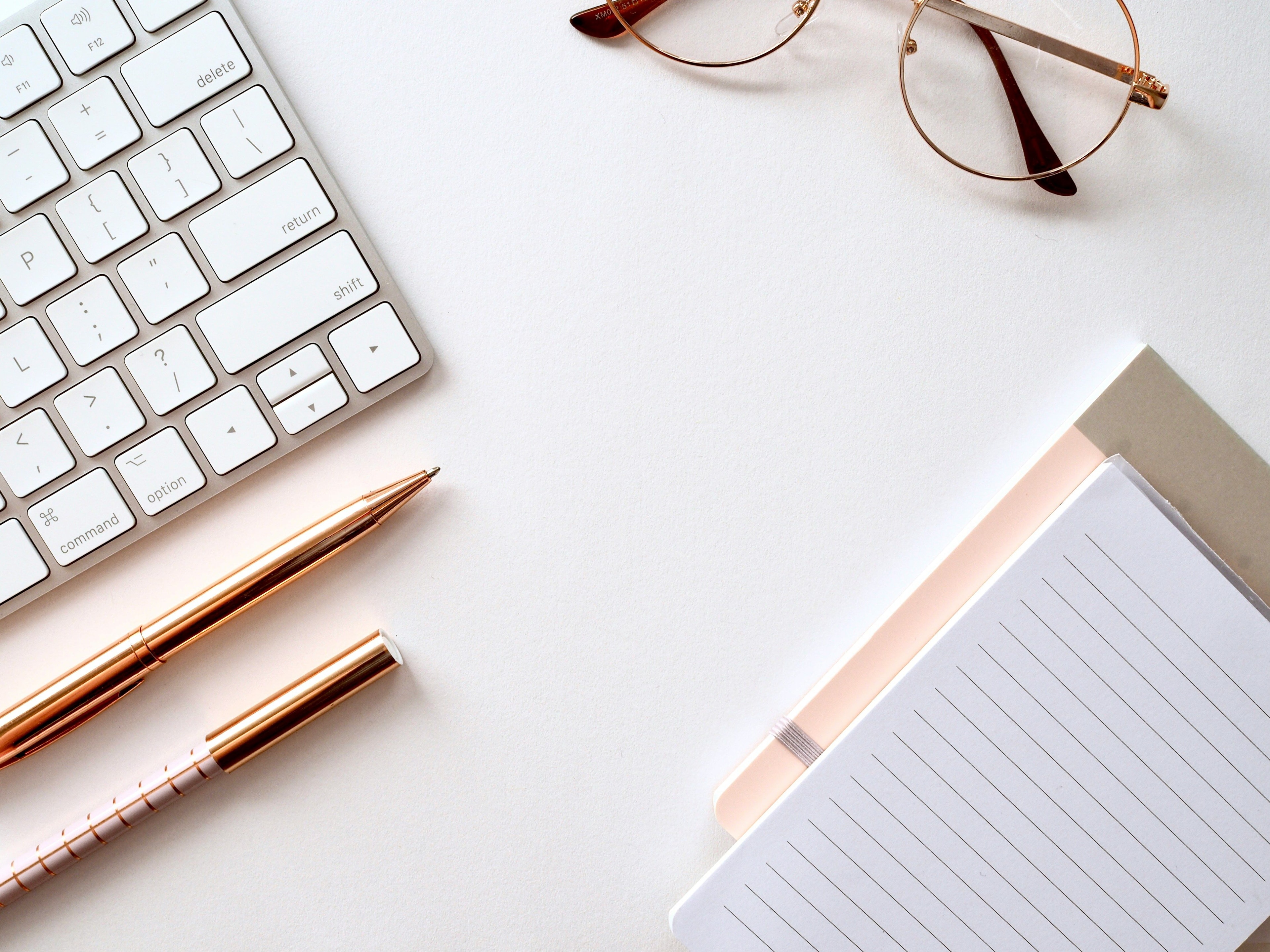 Notepad, pens, and keyboard on desk